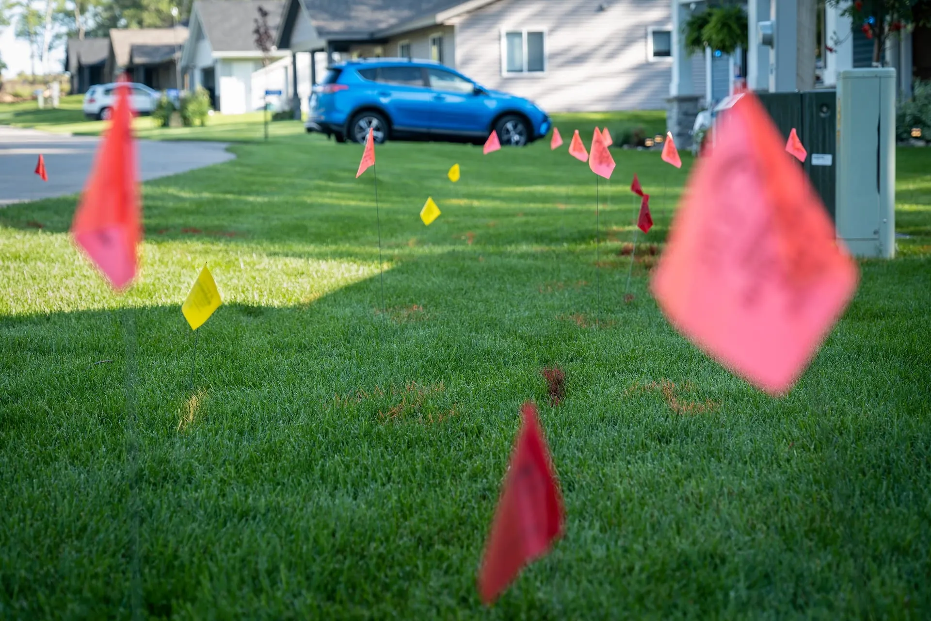 Utility locate flags marking underground lines on a residential front lawn